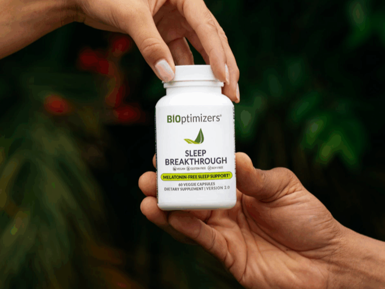 Two hands passing a BiOptimizers Sleep Breakthrough bottle — melatonin-free sleep support, outdoor lifestyle shot